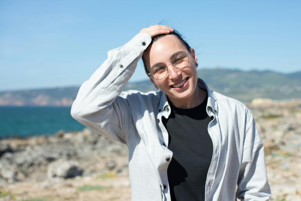 person standing, smiling at the camera with glasses on and their hand on their head in a shrug motion with a nice view of water behind them | North Star Treatment
