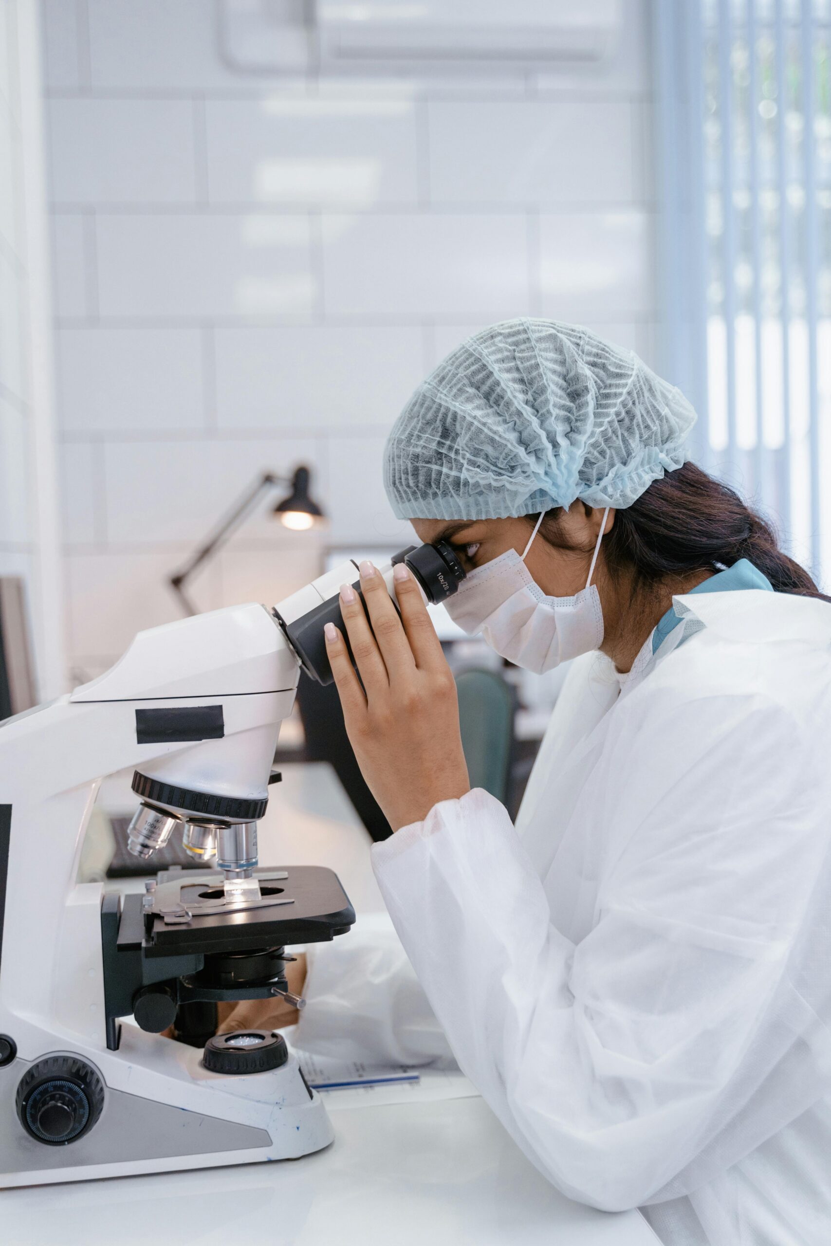 Scientist using a microscope in a modern laboratory while researching addiction science, mental health, and advanced treatment methods in a clinical healthcare setting.